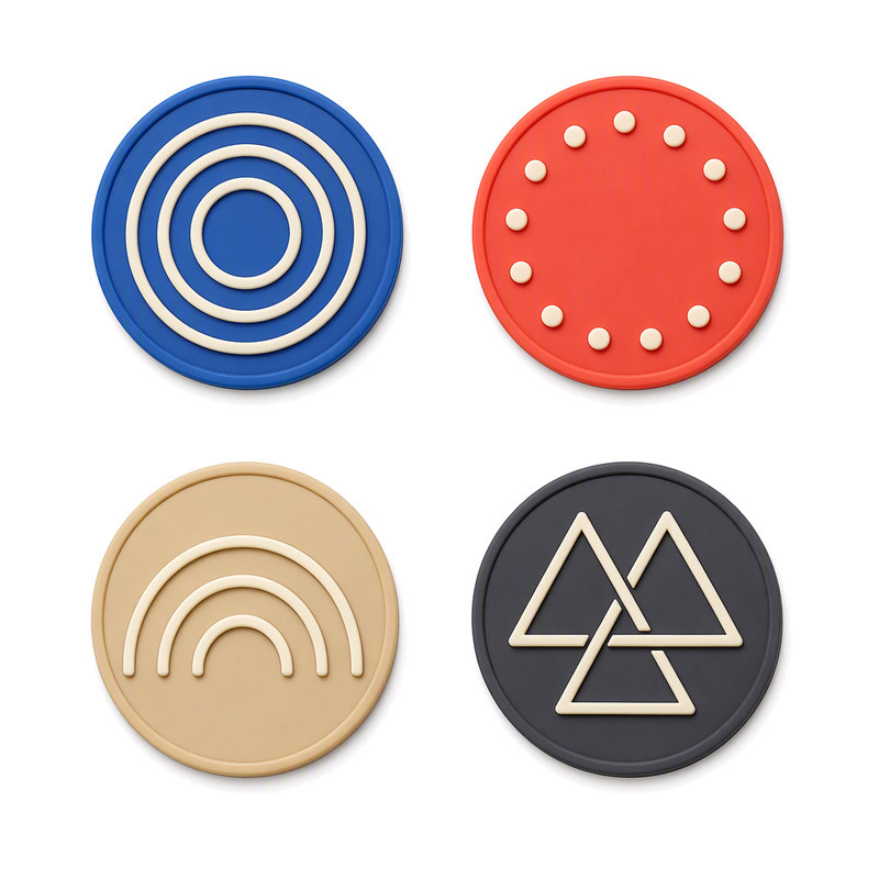 Four round silicone heat transfer patches with line art motifs in different colours, shown to compare surface finish after heat application