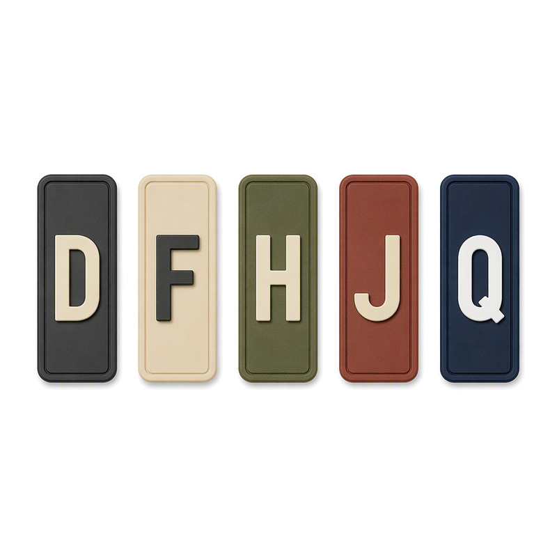 Vertical silicone heel tab labels with raised single letters D, F, H, J and Q in five different base colours