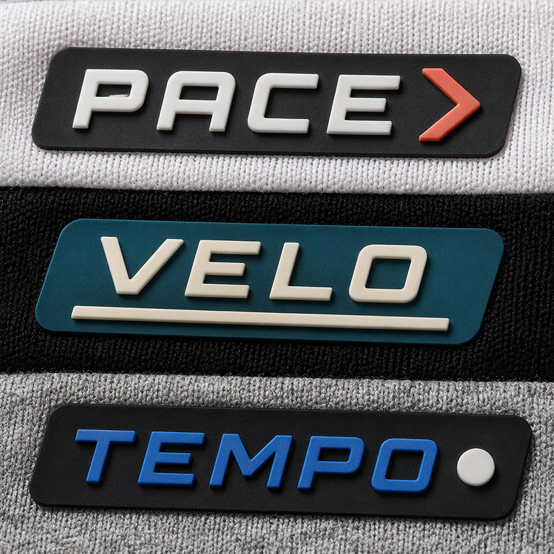 Three 3D molded silicone labels with raised lettering on white, black and gray sportswear knit panels for clothing branding
