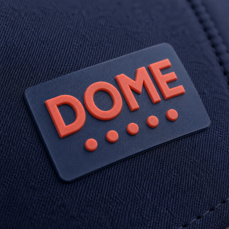 Molded 3D silicone patch with raised orange lettering and dot marks on a navy twill cap panel