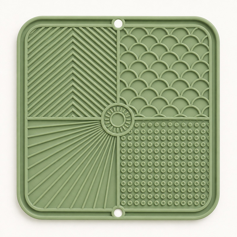 Sage green silicone lick mat with four separate texture zones and visible suction cups at the corners, photographed on a pale mint background