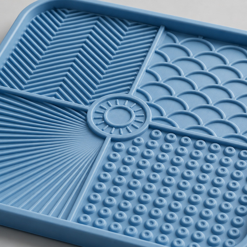 Close view of a blue silicone lick mat with four different texture zones, showing raised bumps, ridges and recessed channels side by side