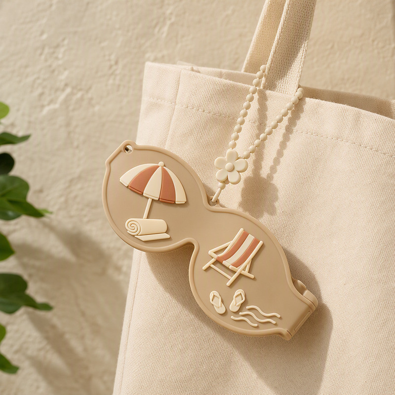 Silicone sunglasses case in sand colour hanging from a canvas tote bag by its beaded strap