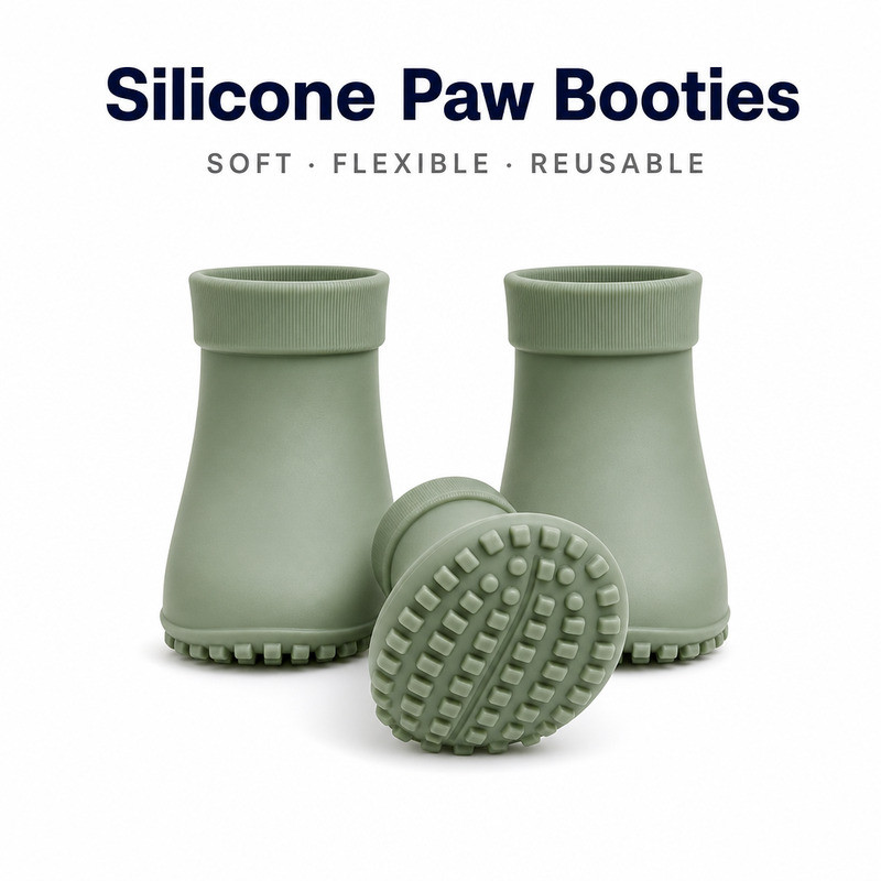 Two silicone pet boots standing upright beside a third turned sole-up, showing the moulded lug pattern and the rolled cuff