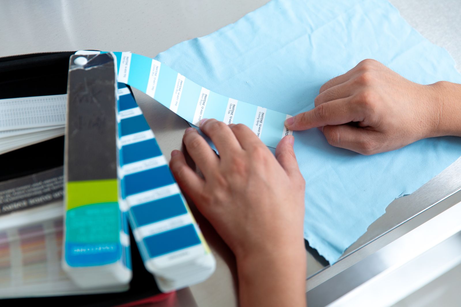 Quality operator matching a Pantone color swatch against fabric before approving a print run