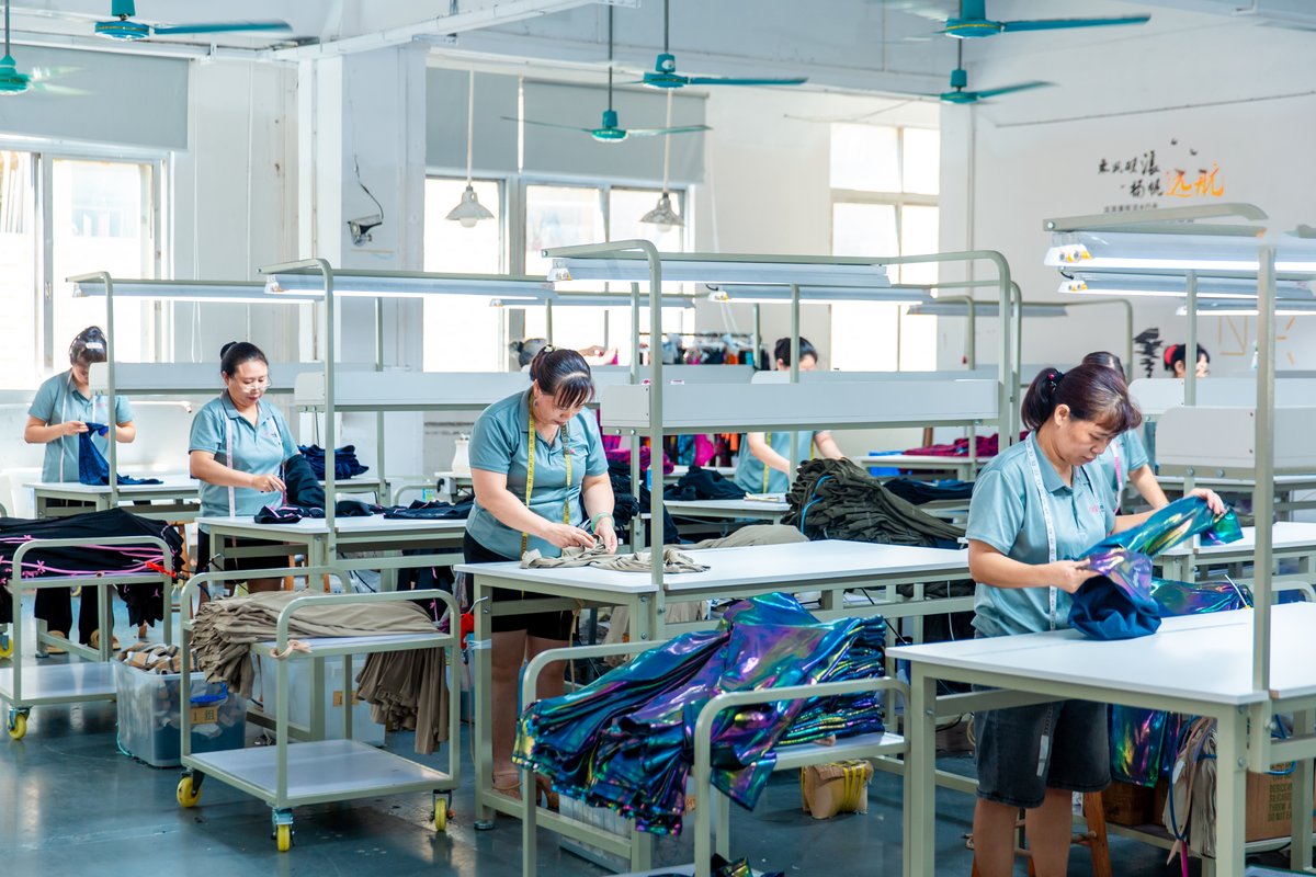 Finishing and QC measuring tables: operators verifying garment measurements against the size tolerance sheet