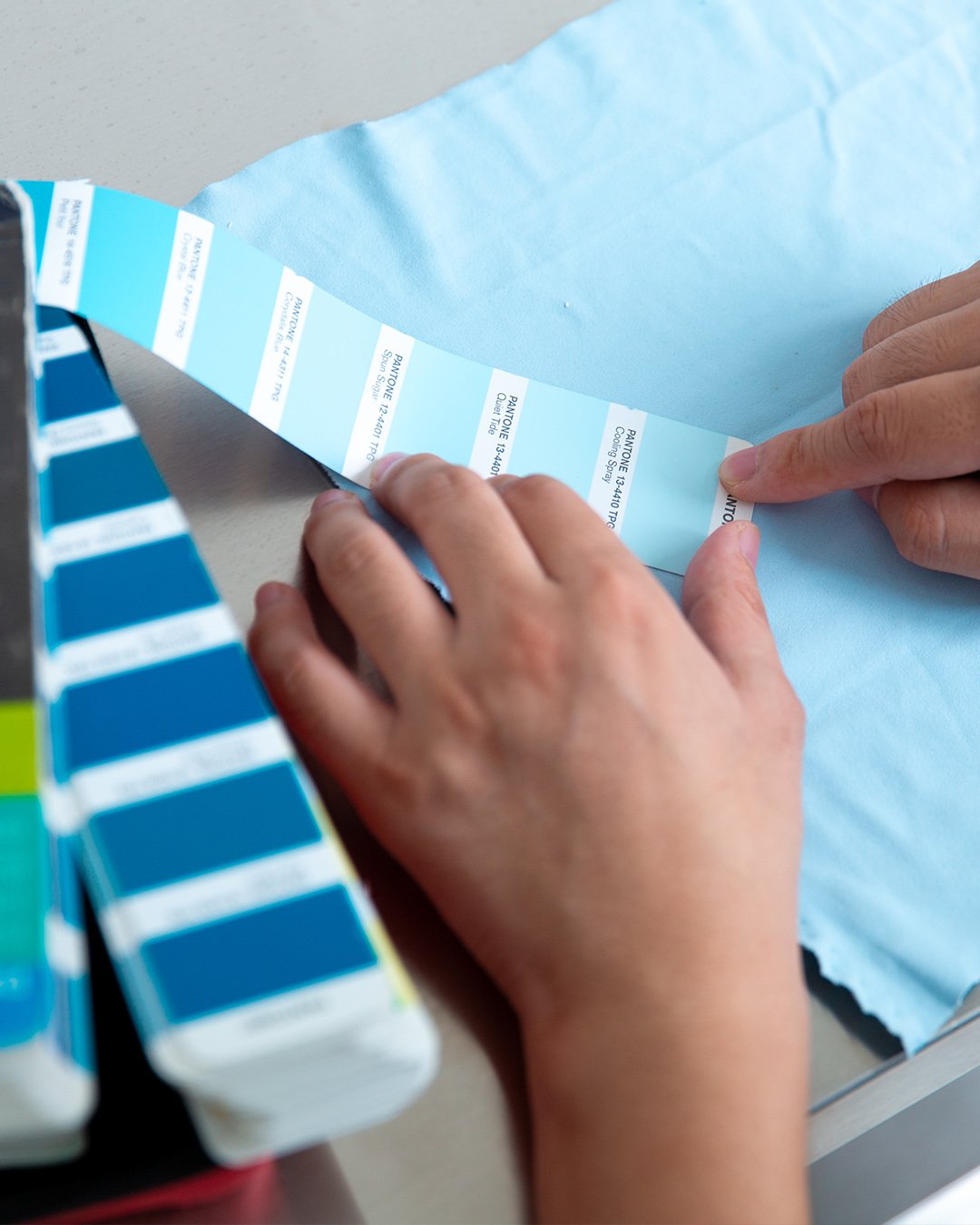 PP sealed sample stage fabric and trim color matching: checking fabric color against a Pantone card to lock bulk color
