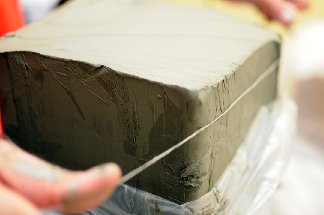 A professional tiler pressing an L-shaped aluminium trim into a bed of mortar on a wall.