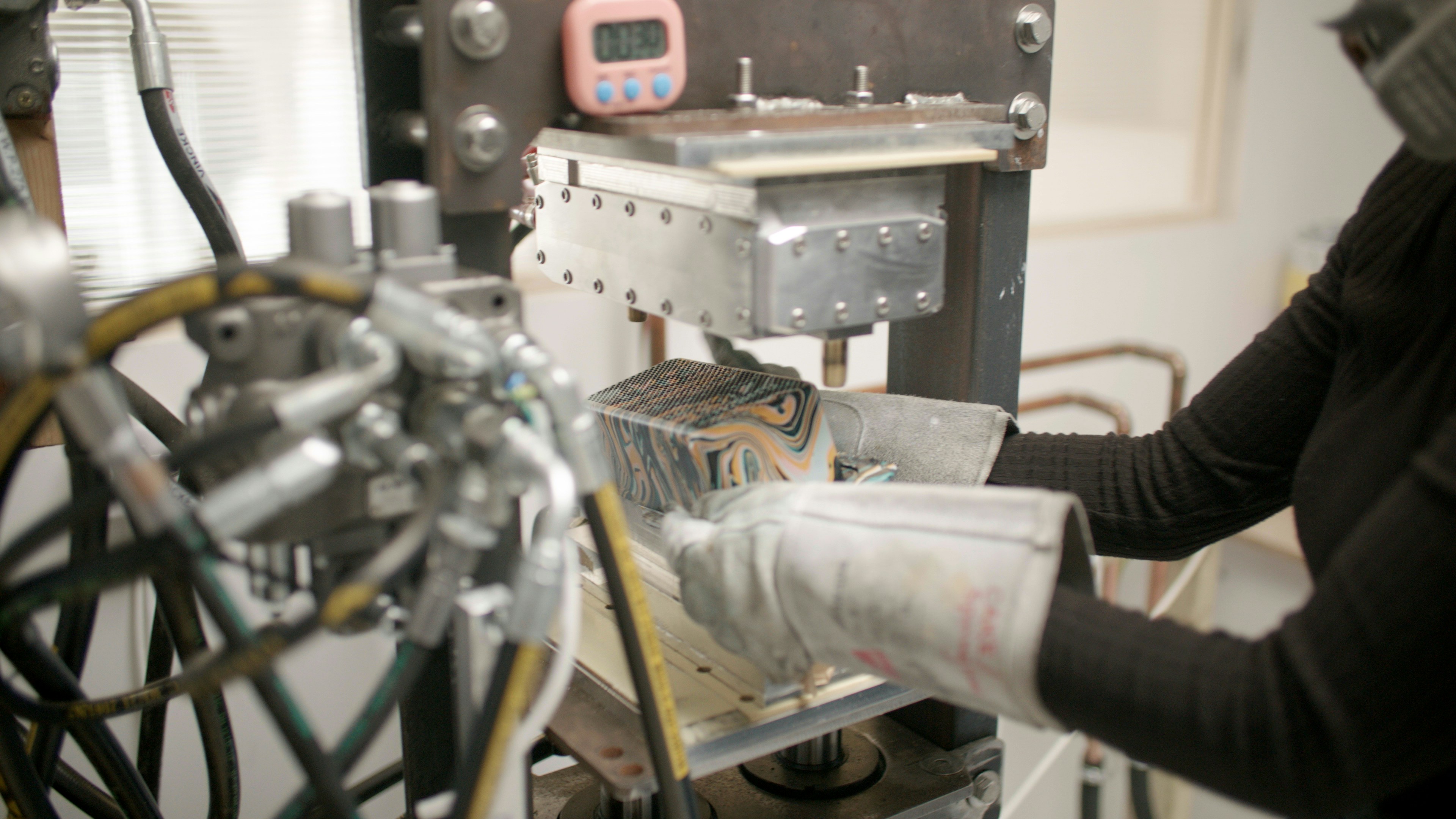 A quality control inspector using a CMM machine to measure a precision metal stamped prototype.