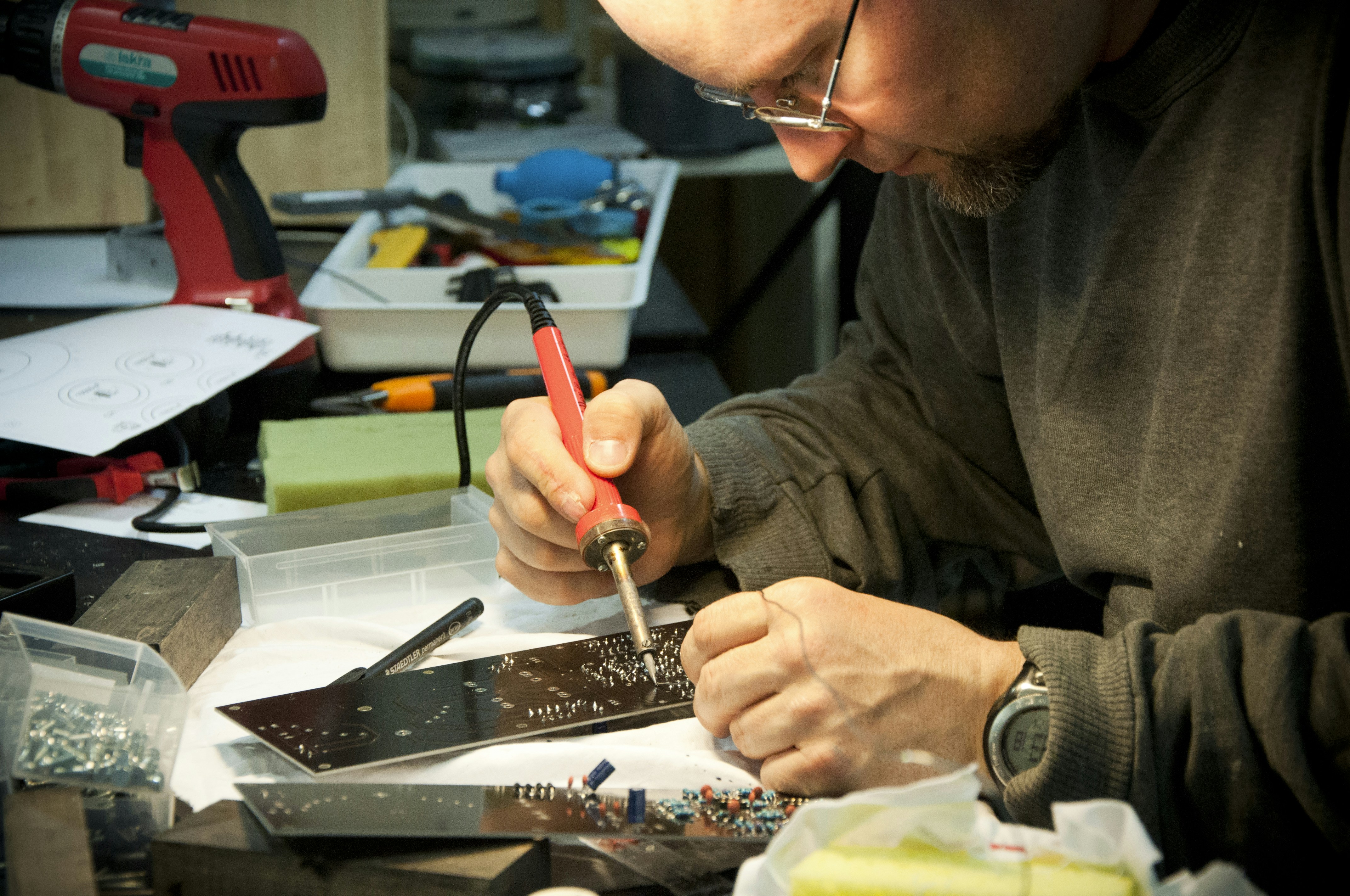 An engineer inspecting a metal stamped prototype with calipers to identify flaws.