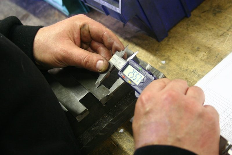 quality control engineer measuring a CNC machined prototype with a digital caliper