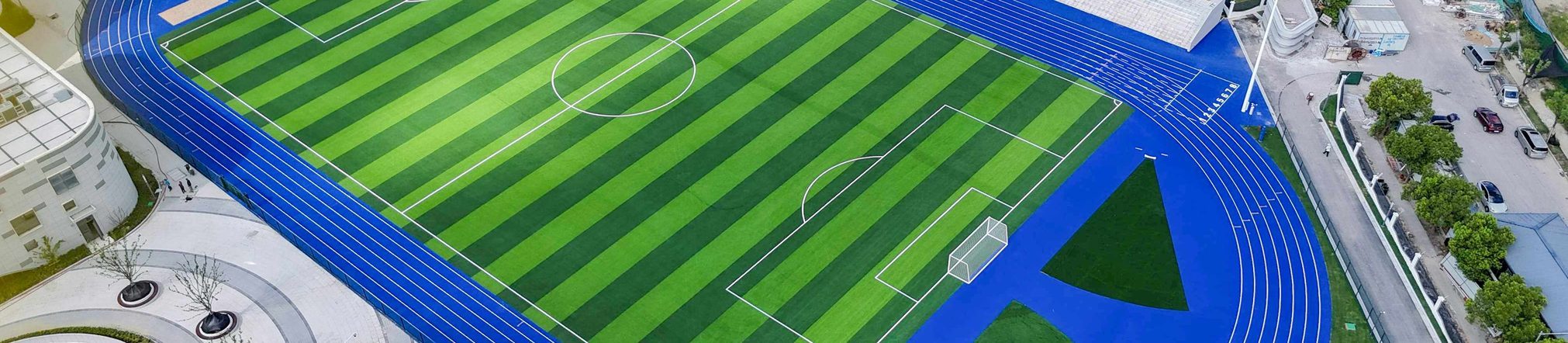 Blue EPDM running track with green football field aerial banner