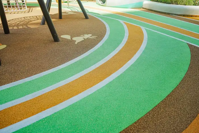 Natural green, ochre and brown EPDM granule color combination integrated into a landscaped path
