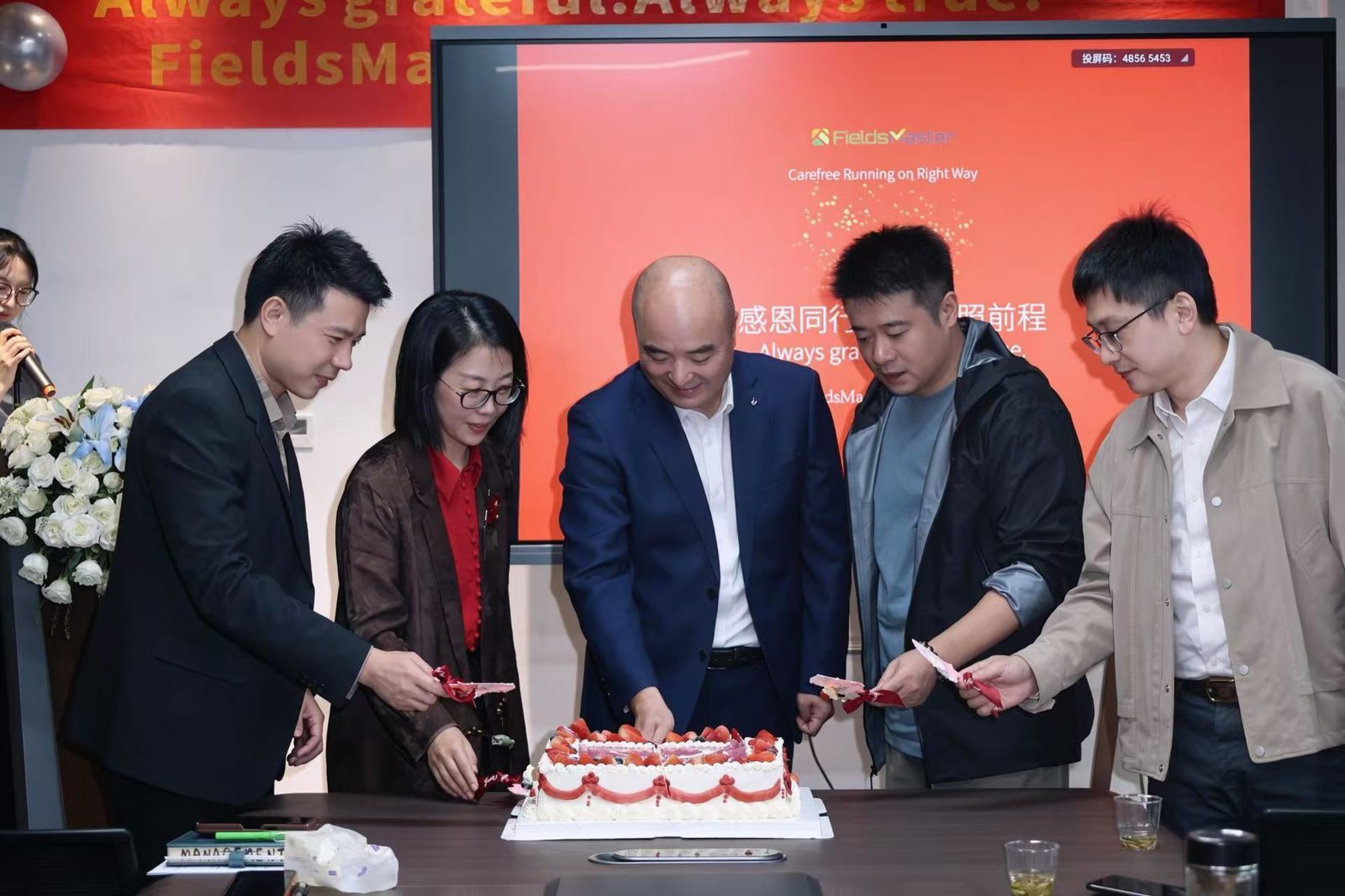 Company leaders cutting the anniversary cake at the FieldsMaster two-year celebration