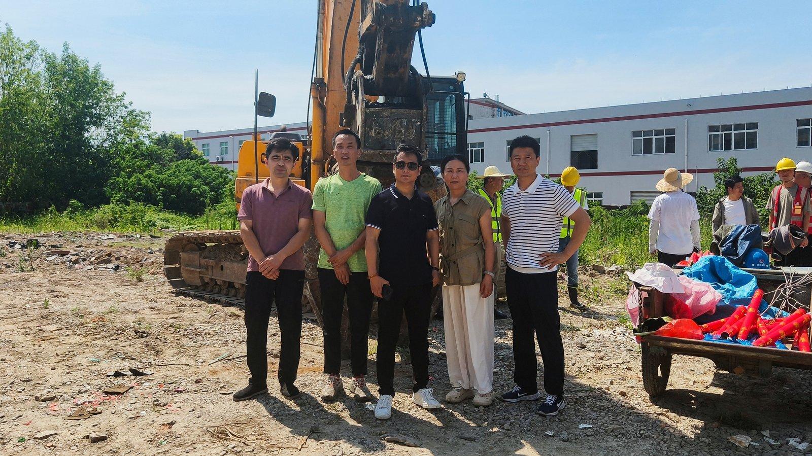 Quanshun Webbing leadership team poses in front of the pile driving rig at the new factory pile driving ceremony