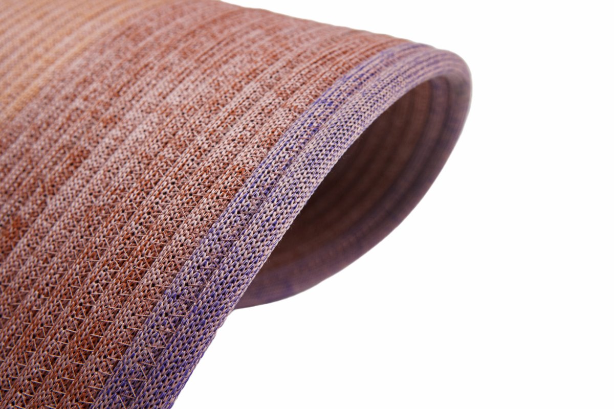 Round rope carpet lifted at the rim showing coil thickness and the bound outer edge