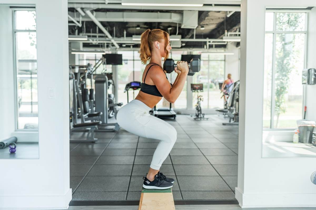Athlete training in a sports bra and leggings with dumbbells