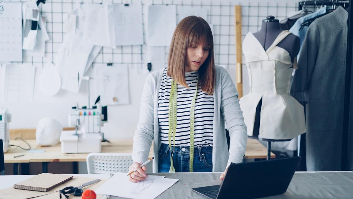 Fashion designer reviewing garment sketches and specifications on a laptop