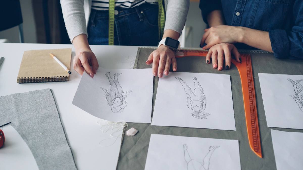 Fashion designers reviewing sketches and fabric options at a worktable