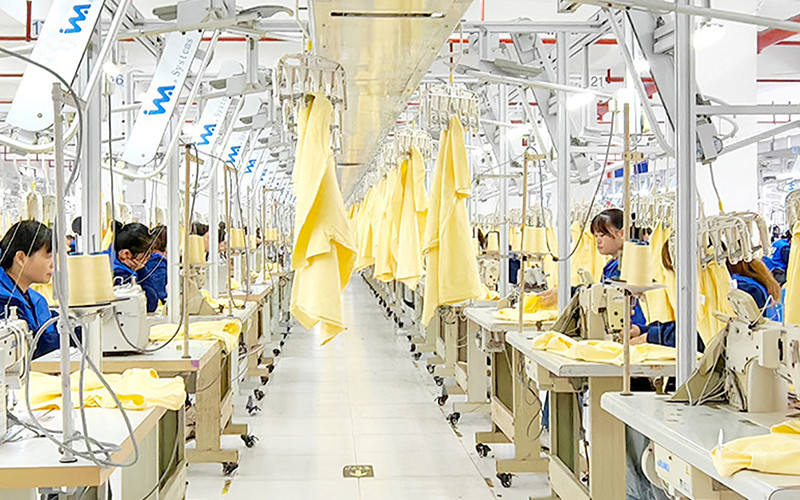 Garment workers using industrial sewing machines in a production workshop