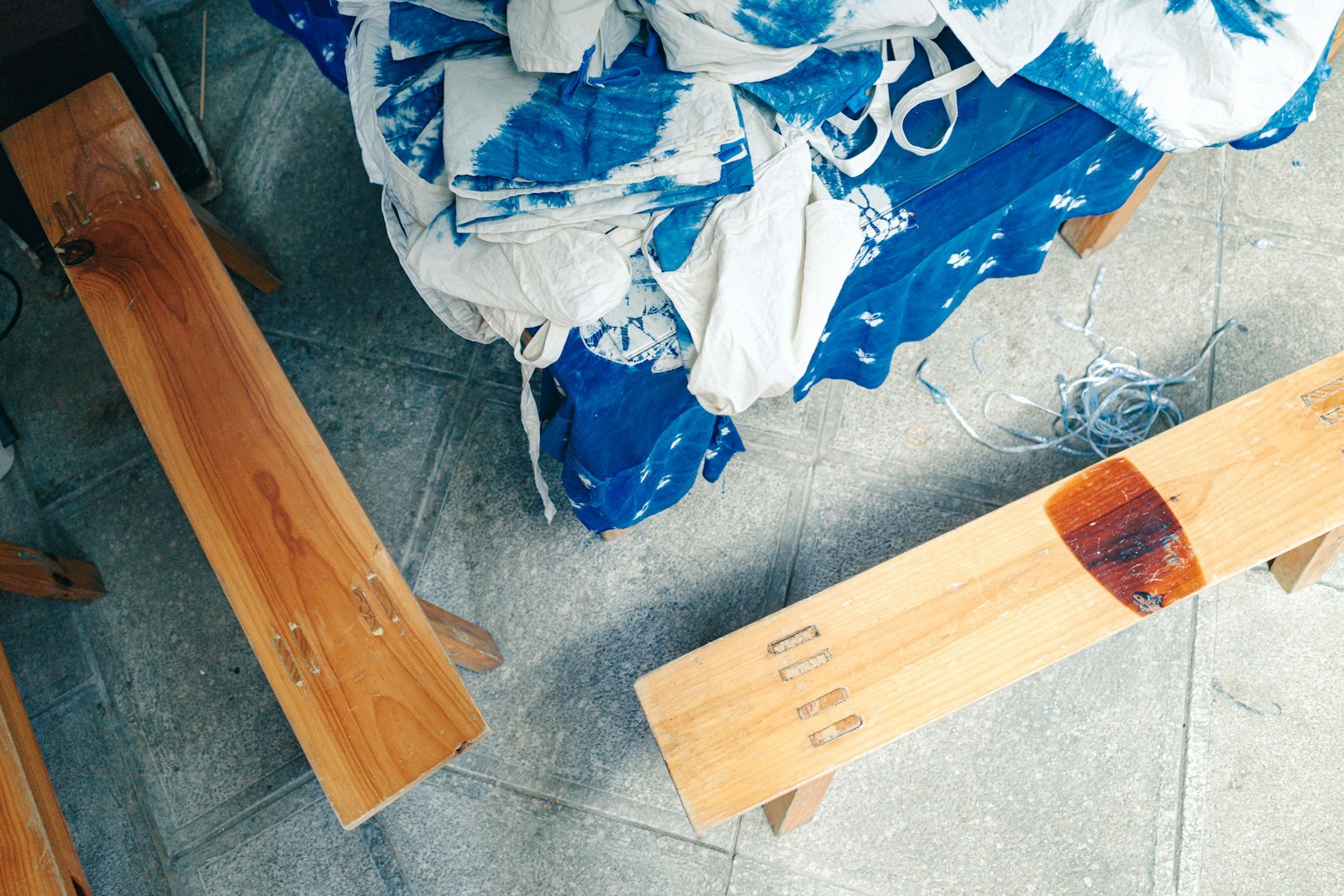 Blue dyed garments and fabric pieces arranged in a dye workshop