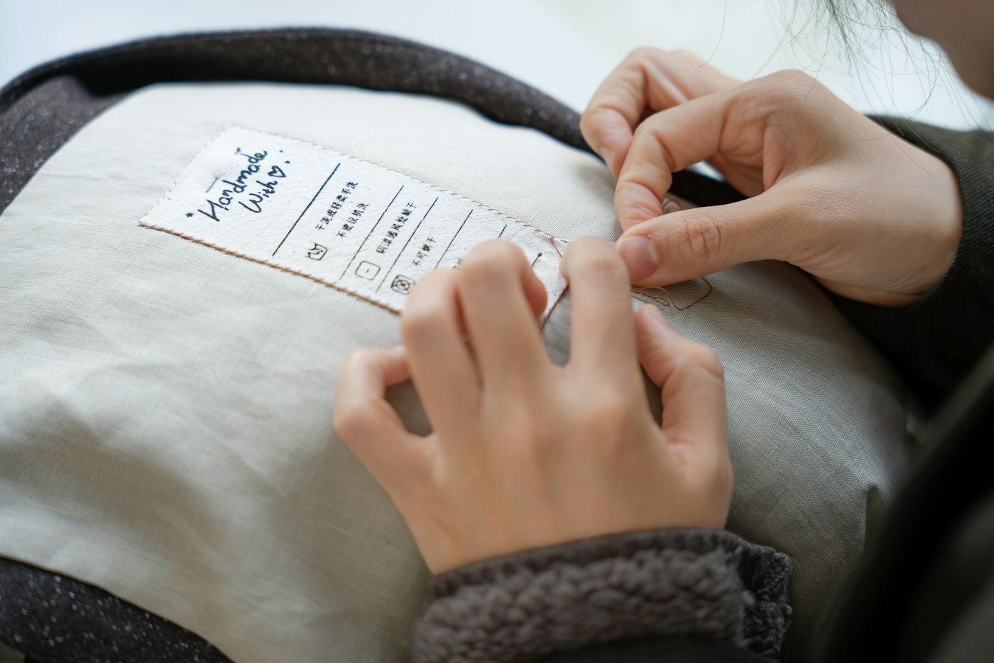 Hands sewing a custom label onto a garment