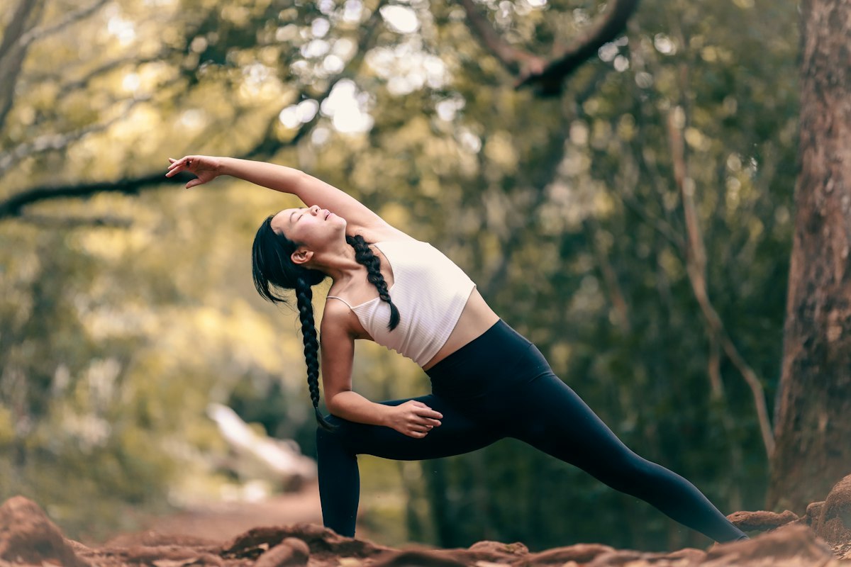 Woman wearing a light crop top and dark leggings during an outdoor yoga stretch