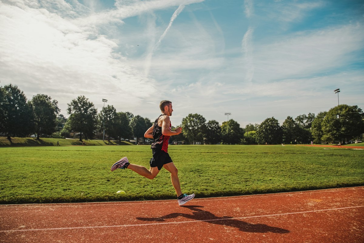 Runner wearing a sports singlet and shorts on an outdoor athletics track
