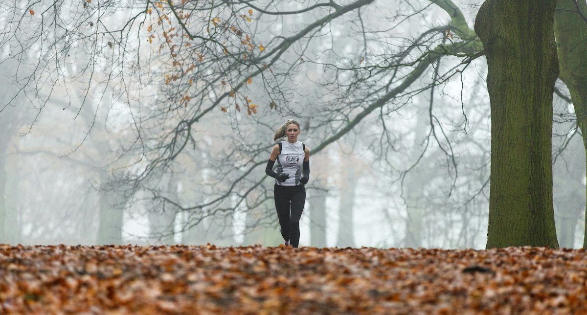 Runner wearing layered sportswear in a misty park