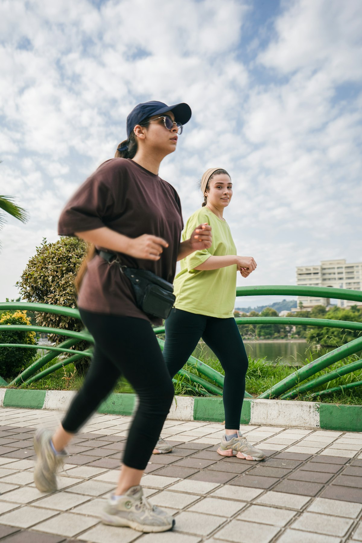 Two women jogging outdoors in training tops and leggings