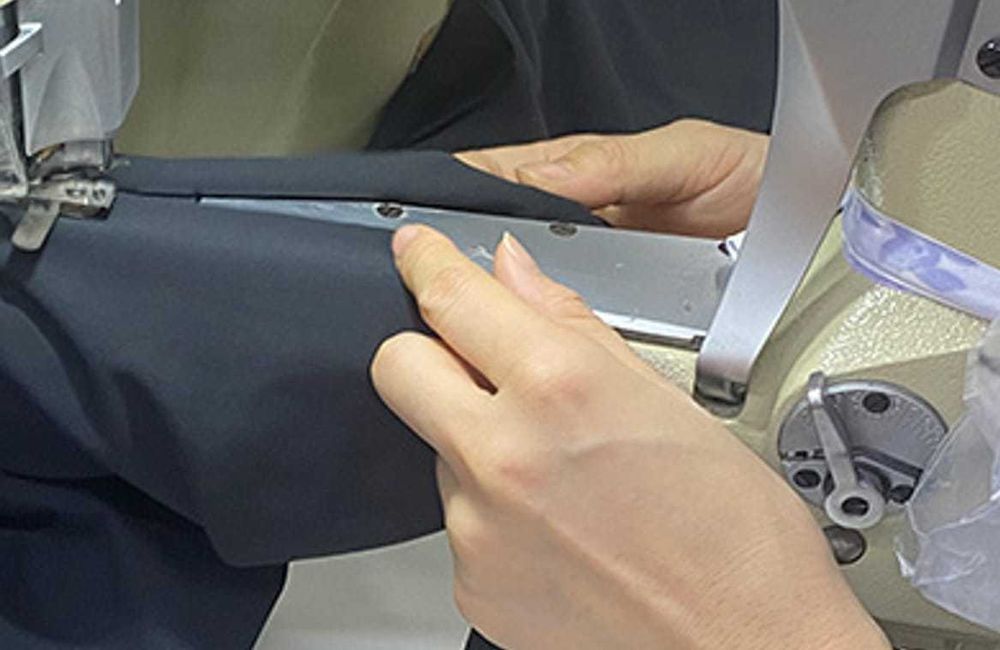 Ohsurewear operator sewing stretch fabric on industrial garment equipment