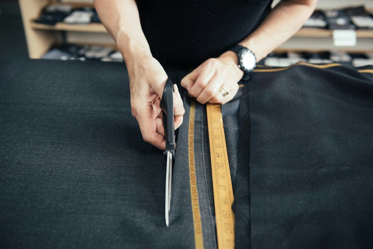 Hands cutting cloth with tailoring scissors