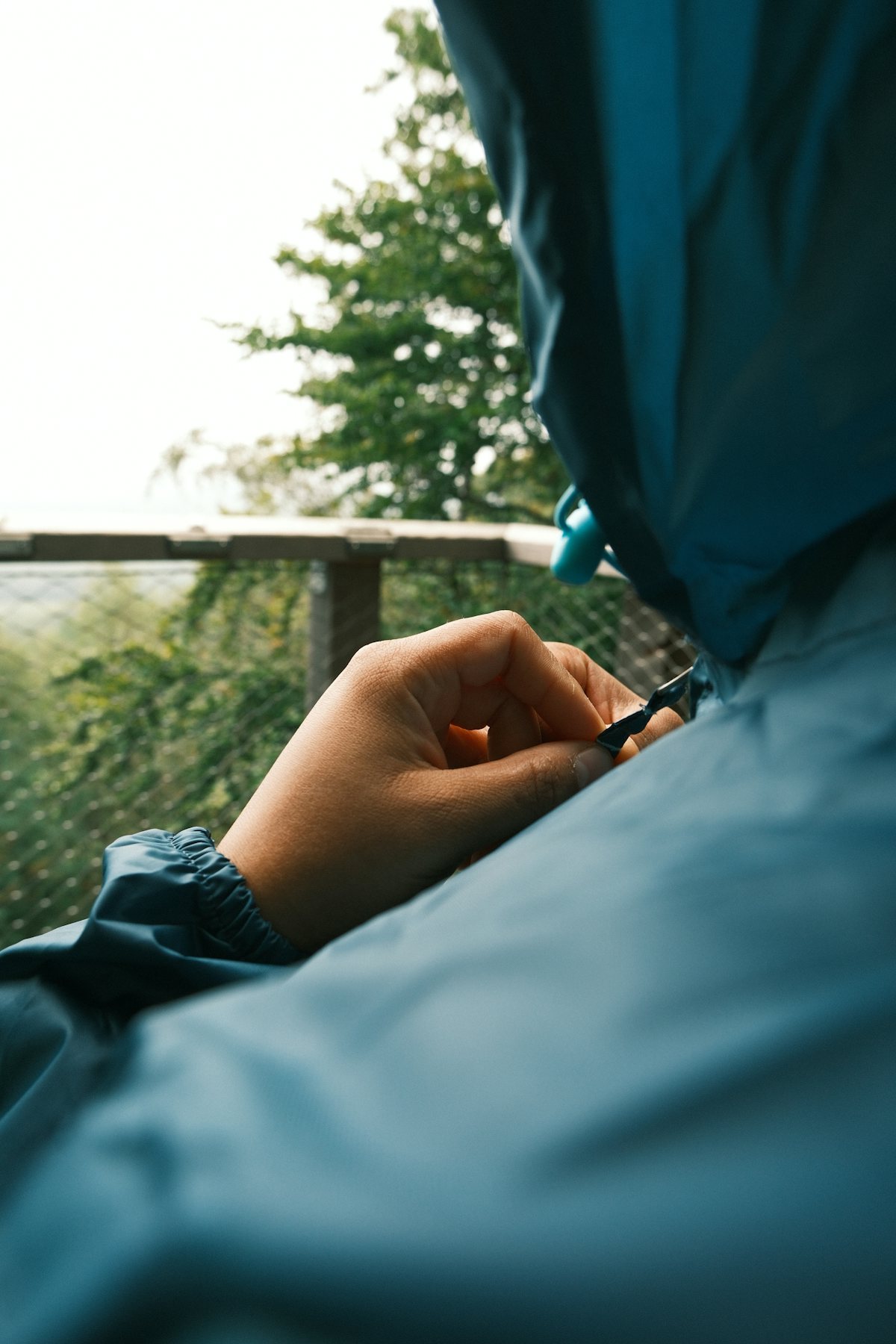 A person operating the zipper of a blue outdoor jacket