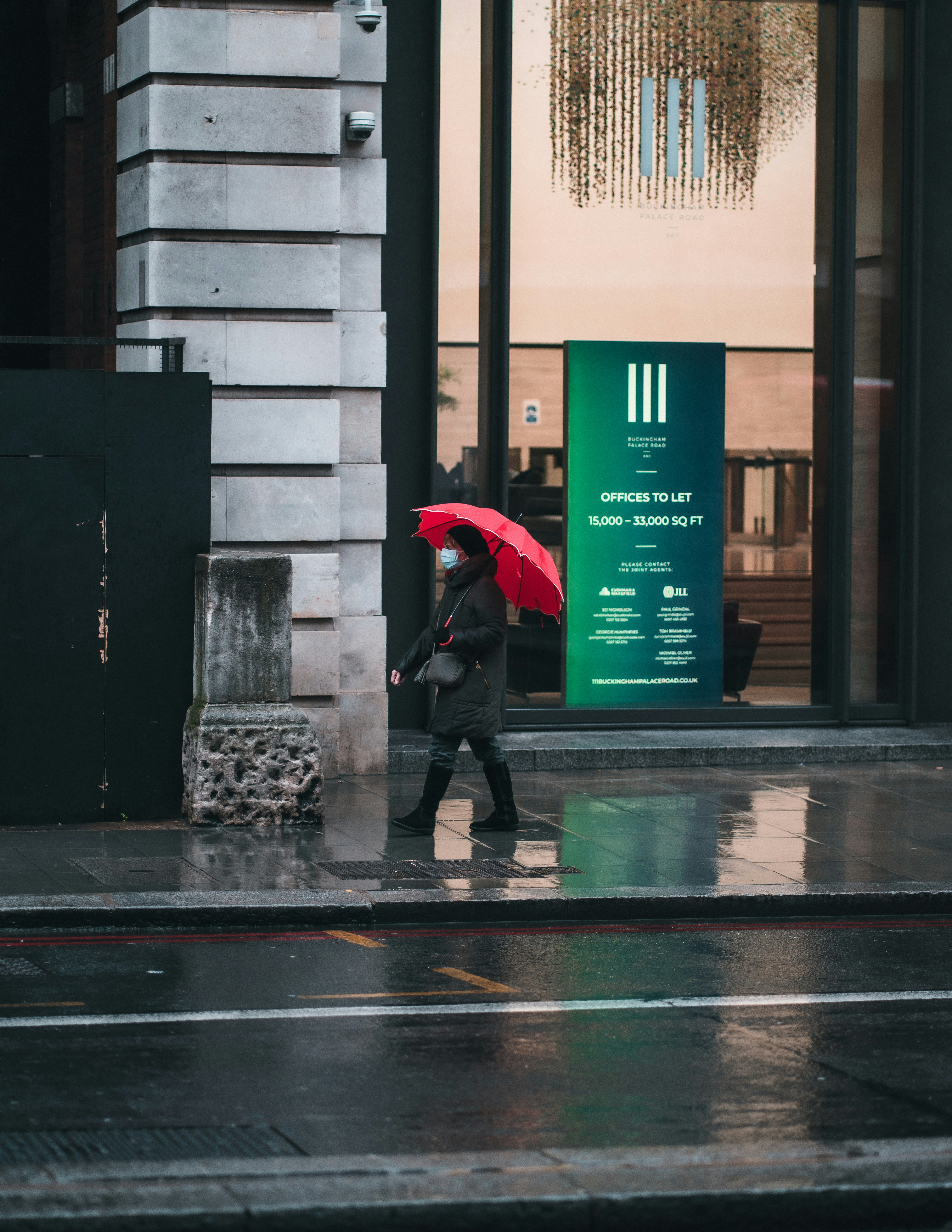 Image of a person wearing a stylish technical jacket in a city environment, with rain falling around them, perfectly dry and comfortable.