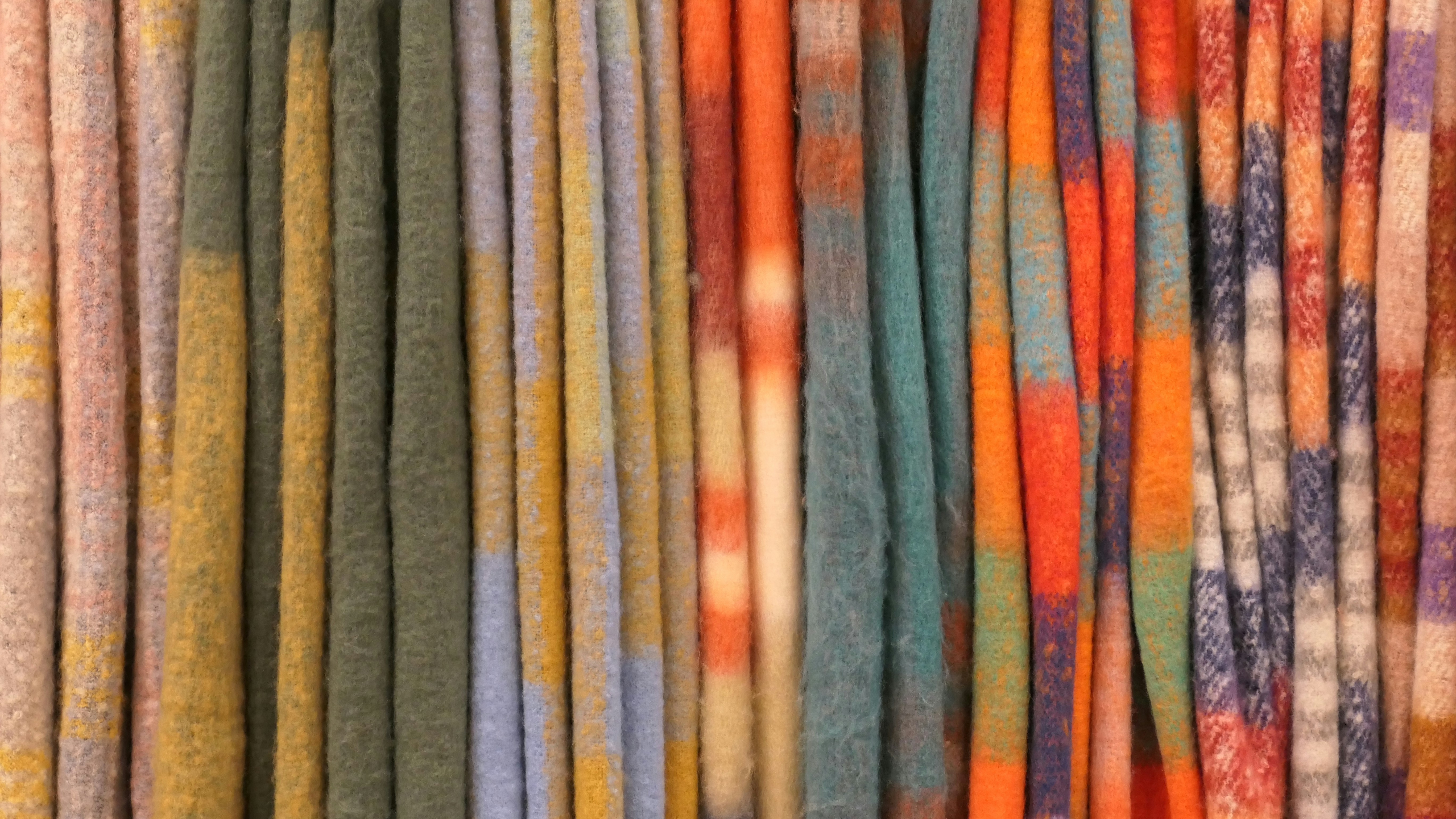 Image of different sustainable fabrics laid out, such as recycled polyester, merino wool, and hemp, with labels indicating their origin.