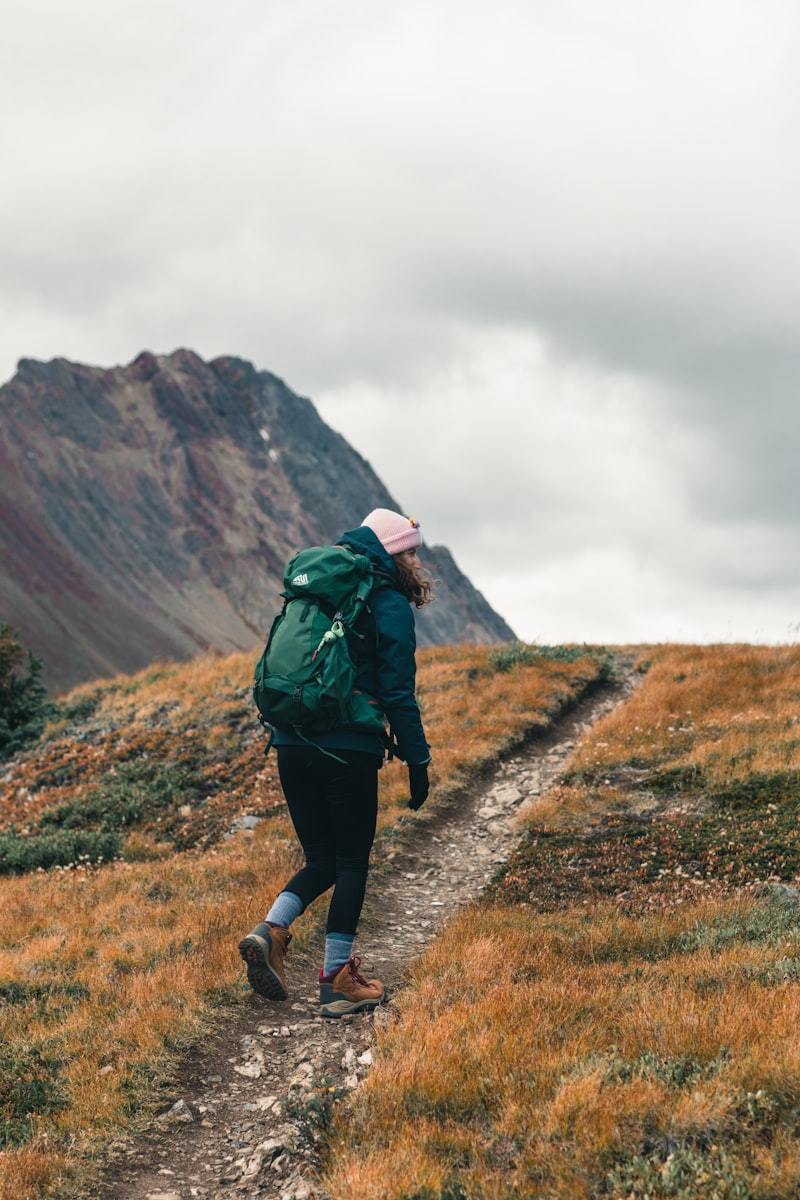 Person in green jacket walking through green grass field