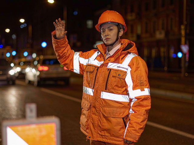 Road crew in hi-vis reflective workwear under night traffic