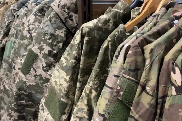Rack of durable custom camo hunting jackets ready for production