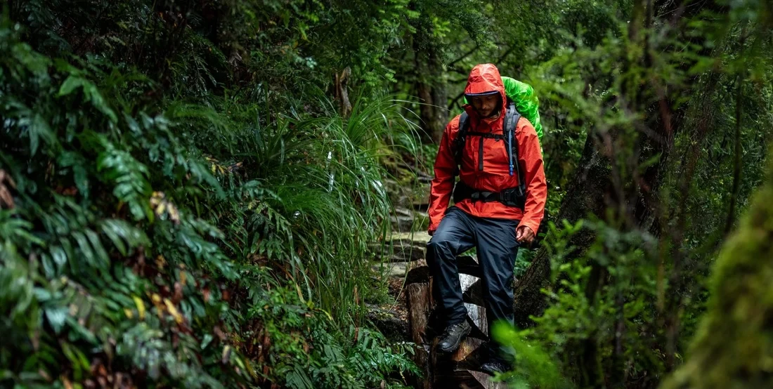 Wanderer in mittelschwerer Outdoorjacke auf einem Bergpfad