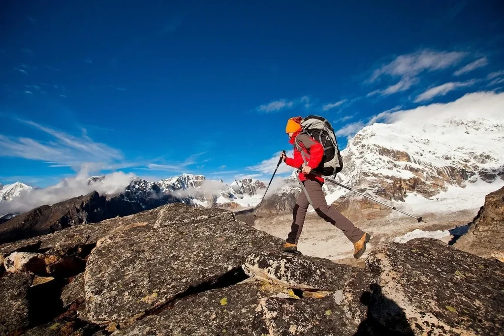 Hiker in a red shell jacket crossing a high alpine ridge