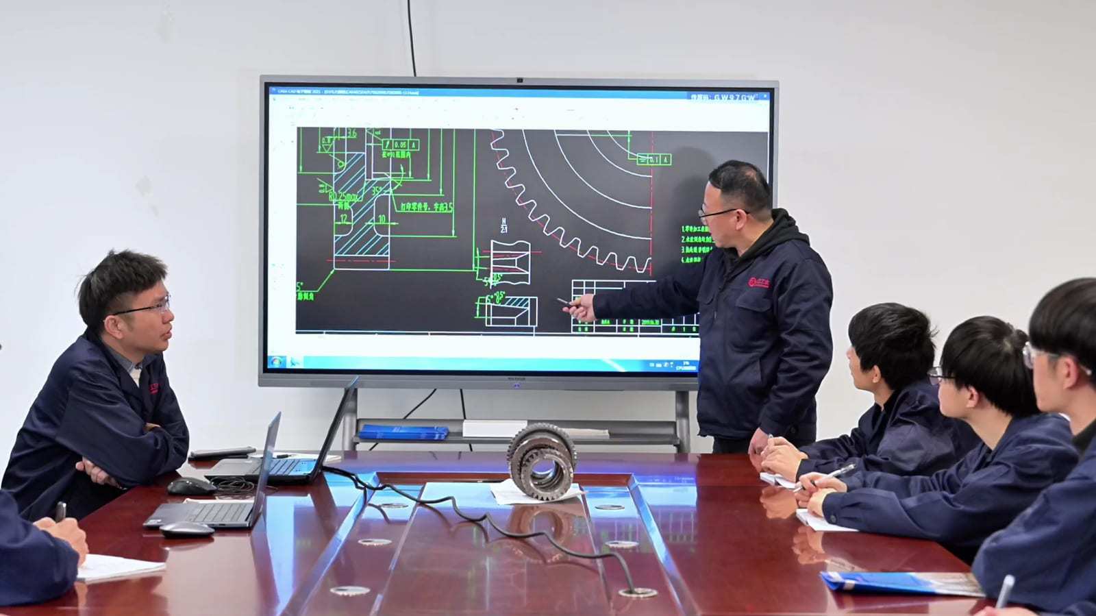 Engineers reviewing a gear drawing and geometry on a screen