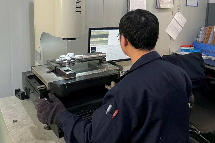 Technician checking shaft perpendicularity on a measuring machine