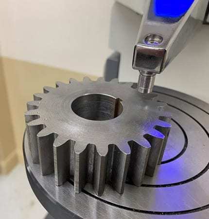 Technician inspecting gear tooth geometry