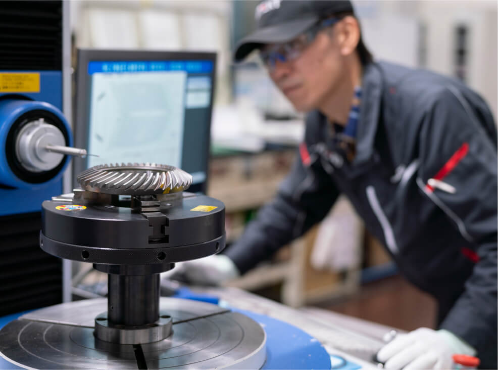 Technician measuring a metal gear on a precision inspection machine.