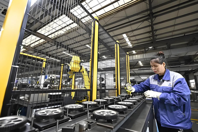 Operator working beside a line of gears in a production workshop