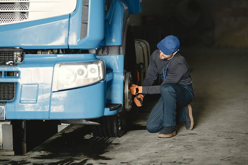 Techniker bei der Prüfung eines Lkw in einer Werkstatt