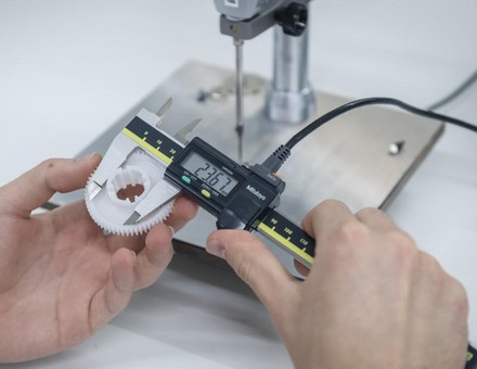 Caliper measuring a plastic gear during dimensional inspection
