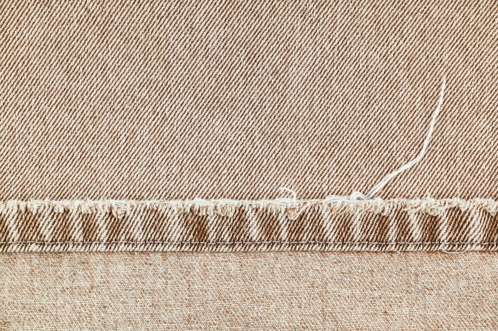 brown-denim-jeans-pants-edge-ripped-stich-on-jean-fabric-background-close-up