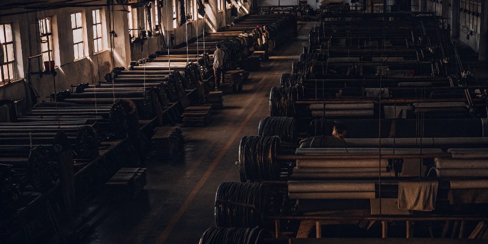 An overhead shot of a clean, organized denim factory floor in China, showing rolls of denim and workstations.