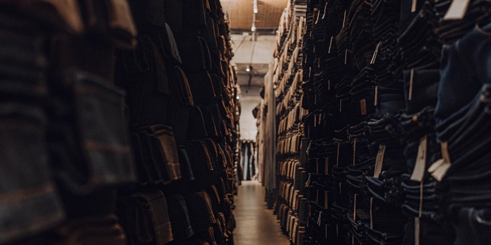 A crowded retail store with walls stacked high with jeans from various major brands.